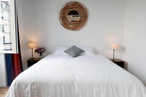 パリにあるアパートメンツ コージーのベッドルーム1室(壁に鏡が付いた白いベッド1台付)