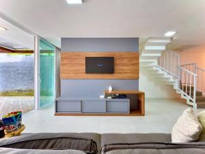 sala de estar con TV y escalera en Casa Completa com Churrasqueira Wi-Fi e Garagem para 2 Carros a 400m da PRAIA Acomoda 8 Pessoas, 3 suites com Ar-Condicionado, en Piçarras