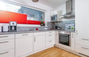 a kitchen with white cabinets and a large window at Schleikante in Olpenitzdorf +19 photos