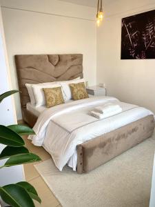 a bedroom with a large bed with white sheets and gold pillows at Valentine's Suite in Nairobi