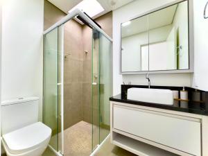 Un baño con inodoro y ducha de cristal. en Casa Completa com Churrasqueira Wi-Fi e Garagem para 2 Carros a 400m da PRAIA Acomoda 8 Pessoas, 3 suites com Ar-Condicionado, en Piçarras 30 fotos más