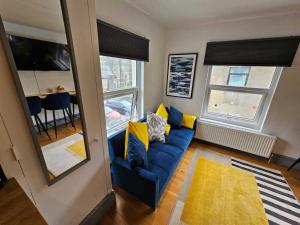 ein Wohnzimmer mit einem blauen Sofa und gelben Kissen in der Unterkunft CityPad Cardiff in Cardiff