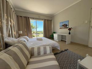 a bedroom with two beds and a couch and a window at Coastal Escape in Struisbaai in Struisbaai
