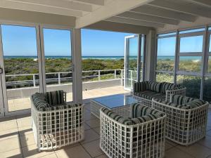 a screened in porch with chairs and a glass table at Coastal Escape in Struisbaai in Struisbaai