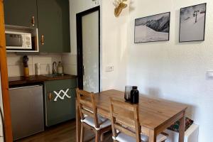 a small kitchen with a wooden table and chairs at The Edelweiss- Renovated studio for 4 people! in Chamrousse +12 photos