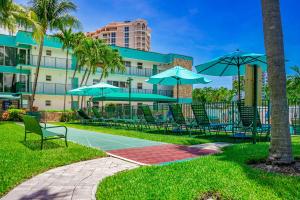 un gruppo di sedie e ombrelloni di fronte a un edificio di Surf Rider Resort a Pompano Beach