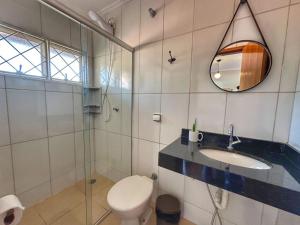 une salle de bain avec toilettes, lavabo et miroir dans l'établissement Pousada Gaia Canastra, à São João Batista do Glória