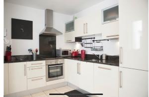 a kitchen with white cabinets and black counter tops at Lovely Duplex close to city and Guinness Factory in Dublin