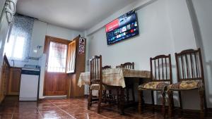 a kitchen with a table and chairs and a television on the wall at Ruralux Mecina Fondales in Mecina Fondales