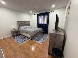 a bedroom with a bed and a flat screen tv at Comfy & Spacious 4BR Family Home with Free Parking, Laundry, BBQ! 10 Min Walk to Headwaters Hospital, 5 Min Drive to Mount Alverno Luxury Resorts, Ideal for Medical, Vacation or Work Stays! in Orangeville