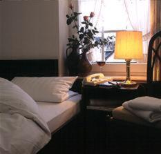 a bedroom with a bed and a table with a lamp at Hotel Matheisen in Cologne
