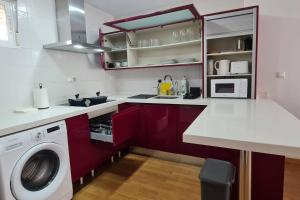 una cucina con armadi rossi e una lavatrice di Apartamento Tranquilo en Altorreal con WiFi a Molina de Segura