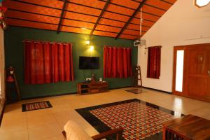 a living room with red curtains and a flat screen tv at Chettinad Courtyard By Shivalaya Coimbatore in Alāndurai