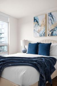 a white bedroom with a bed with blue pillows at Stylish 1BR Condo Near Toronto Top Attractions in Toronto