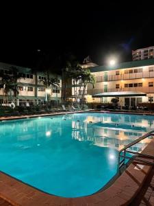 una grande piscina di fronte a un edificio di notte di Surf Rider Resort a Pompano Beach
