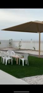 a row of white tables and chairs under an umbrella at Sunrise Oasis واحة الشروق للضيافة in Sur