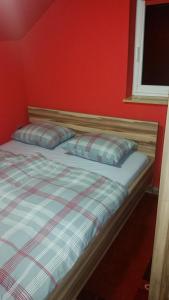 - un lit avec deux oreillers et un mur rouge dans l'établissement Apartment Borovnica Rogla, à Resnik