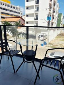 een glazen tafel en 2 stoelen op een balkon bij Summer Flat 208 in Ilha da Restinga