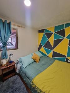 a bedroom with a bed with a colorful wall at El chalet del Gato, Loft en hermoso barrio central Viña del Mar in Viña del Mar