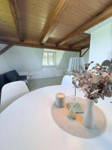 a white table with a vase and a lamp on it at Home of well-being for everyday life in Bissegg