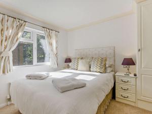 a bedroom with a large white bed with two windows at 3 Bed in Okehampton 95636 in Okehampton