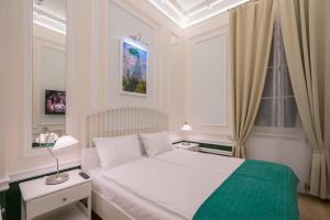 a bedroom with a white bed with a green blanket at Revelton Suites Karlovy Vary in Karlovy Vary