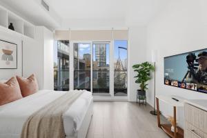 a white bedroom with a large bed and a flat screen tv at Modern Studio-Style Condo in Downtown Toronto in Toronto +16 photos
