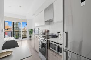 a kitchen with white cabinets and a refrigerator at Modern Studio-Style Condo in Downtown Toronto in Toronto