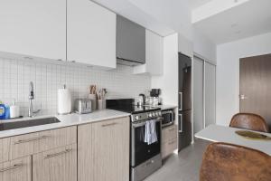 a kitchen with white cabinets and a stove top oven at Modern Studio-Style Condo in Downtown Toronto in Toronto