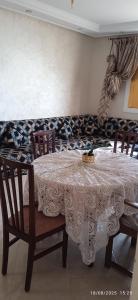 a dining room table with two chairs and a white lace table cloth at Appartement azla plage in Oulad Akkou