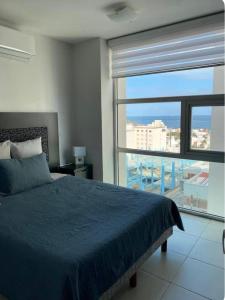 a bedroom with a blue bed and a large window at Sea View 10 Boca Towers in Boca del Río
