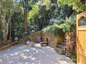 a patio with two chairs and a stone wall at Stone Cottage With Sea Views in Wilderness