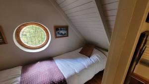a small attic room with a bed and a window at Stone Cottage With Sea Views in Wilderness +14 photos