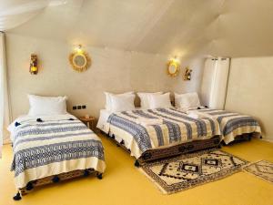 two beds in a room with yellow floors at Merzouga Top Camping in Merzouga +23 photos