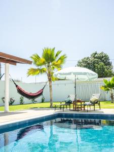 a swimming pool with two chairs and a hammock at Kite Oasis Parajuru Casa Ilha in Parajuru