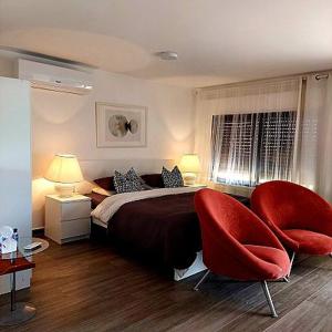 マダバにあるThe Placeのベッドルーム1室(ベッド1台、赤い椅子2脚付)