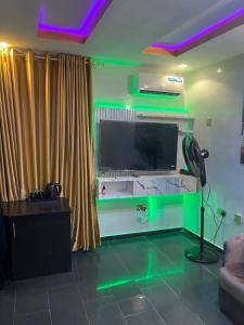 a living room with a large tv and green lights at DEVHAK Hotel and Suites in Warri