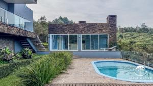 ein Haus mit einem Swimmingpool vor dem Haus in der Unterkunft Casa com piscina 3 suítes a 15 min Centro Gramado in Gramado
