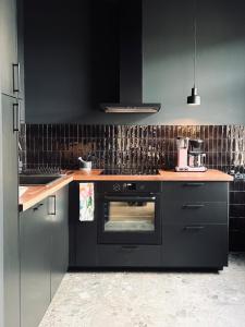 Una cocina con horno negro y gabinetes negros. en Atelier Noé NOIR - Kunstvoll Wohnen - Wunderbares Frühstück möglich - Ruhig und nah am Zentrum -, en Chemnitz