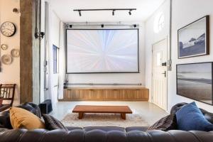 a living room with a couch and a large screen at CasaAzul Moderna&Confortável Campinas in Campinas