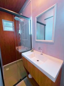 a bathroom with a sink and a glass shower at São Francisco de Paula - Quarto Confortável na Serra! in São Francisco de Paula