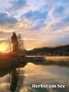 a view of a lake with the sun setting at SeeHotel & SeeApartments Kärntnerhof- direkt am See! in Weissensee