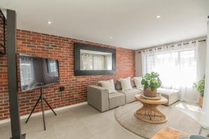 a living room with a brick wall and a tv at Lovemore Retreat - Port Elizabeth in Gqeberha