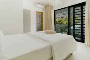 une chambre avec un lit blanc avec une grande fenêtre dans l'établissement VILLA BRABANT - West Coast, Private Villas Resort, à Rivière Noire 36 autres photos