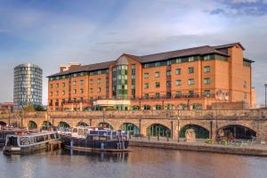 a large brick building next to a river with boats at Sandman Signature Sheffield Quays Hotel in Sheffield