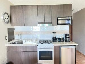 a kitchen with a stove and a sink and a microwave at Incredible Suite Cancun - BEACH CONDO - 6PX in Cancún