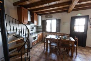 a kitchen with a table and chairs and a staircase at Complejo turístico Las Mimosas del Nalon in San Juan de la Arena