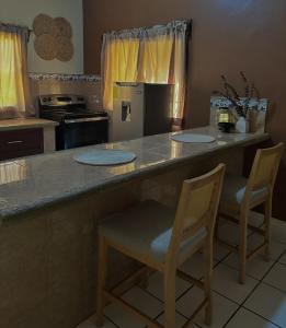 a kitchen with a counter with two chairs and a stove at Apartamento Céntrico y Acogedor in Comayagua +6 photos