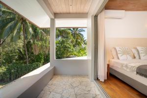 モーレア島にあるMoorea Temae Villa walking dist beach and golfのベッドと大きな窓のある寝室