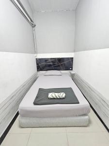 une petite pièce avec un lit avec un oreiller dessus dans l'établissement Future Hostel Pattaya, à Nong Prue